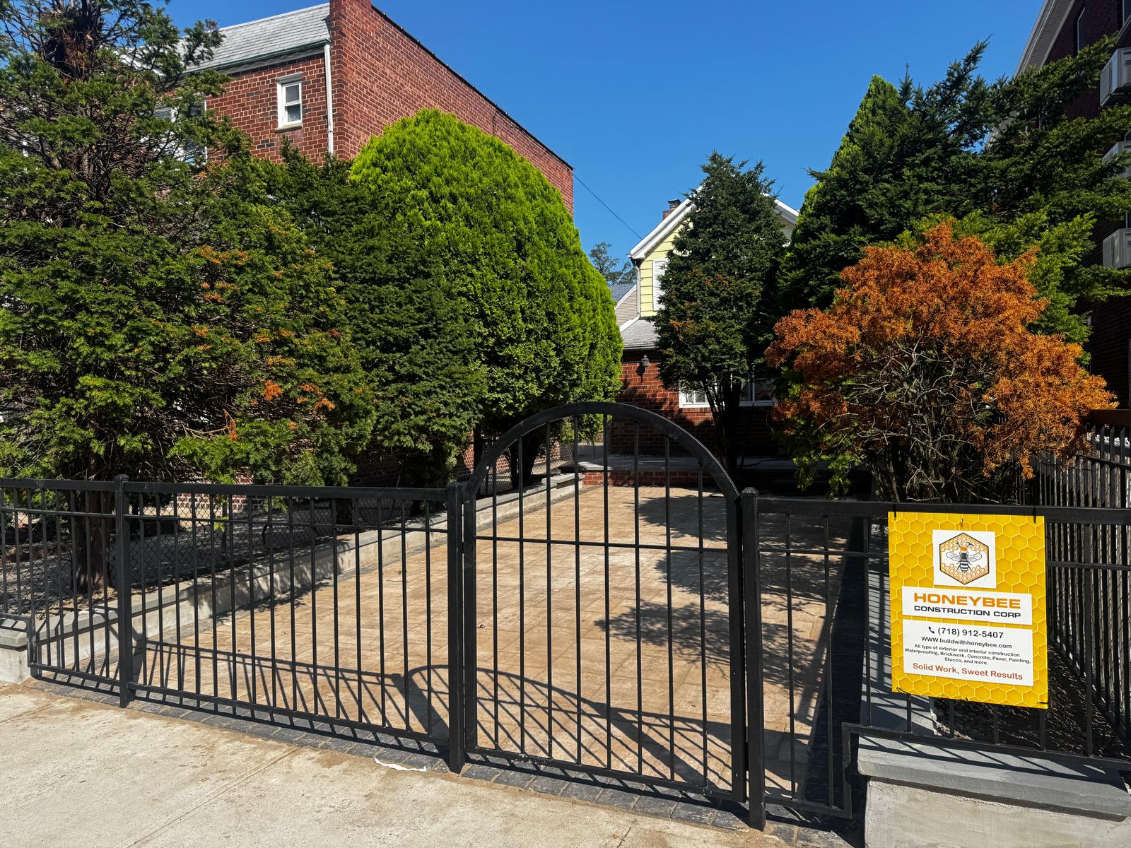 New paver driveway and black aluminum fence with arched gate — photo 1